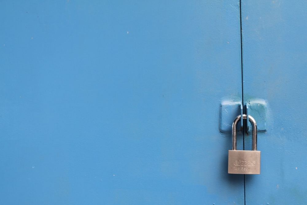 Gembok logam menggantung di pintu berwarna biru sebagai simbol keamanan digital