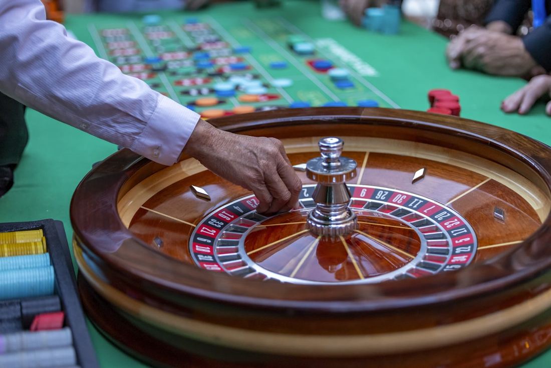 Dealer memutar roda roulette di meja kasino berwarna hijau